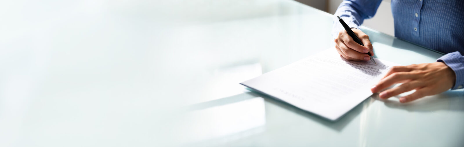 Businesswoman's Hand Signing Contract With Pen Over Desk