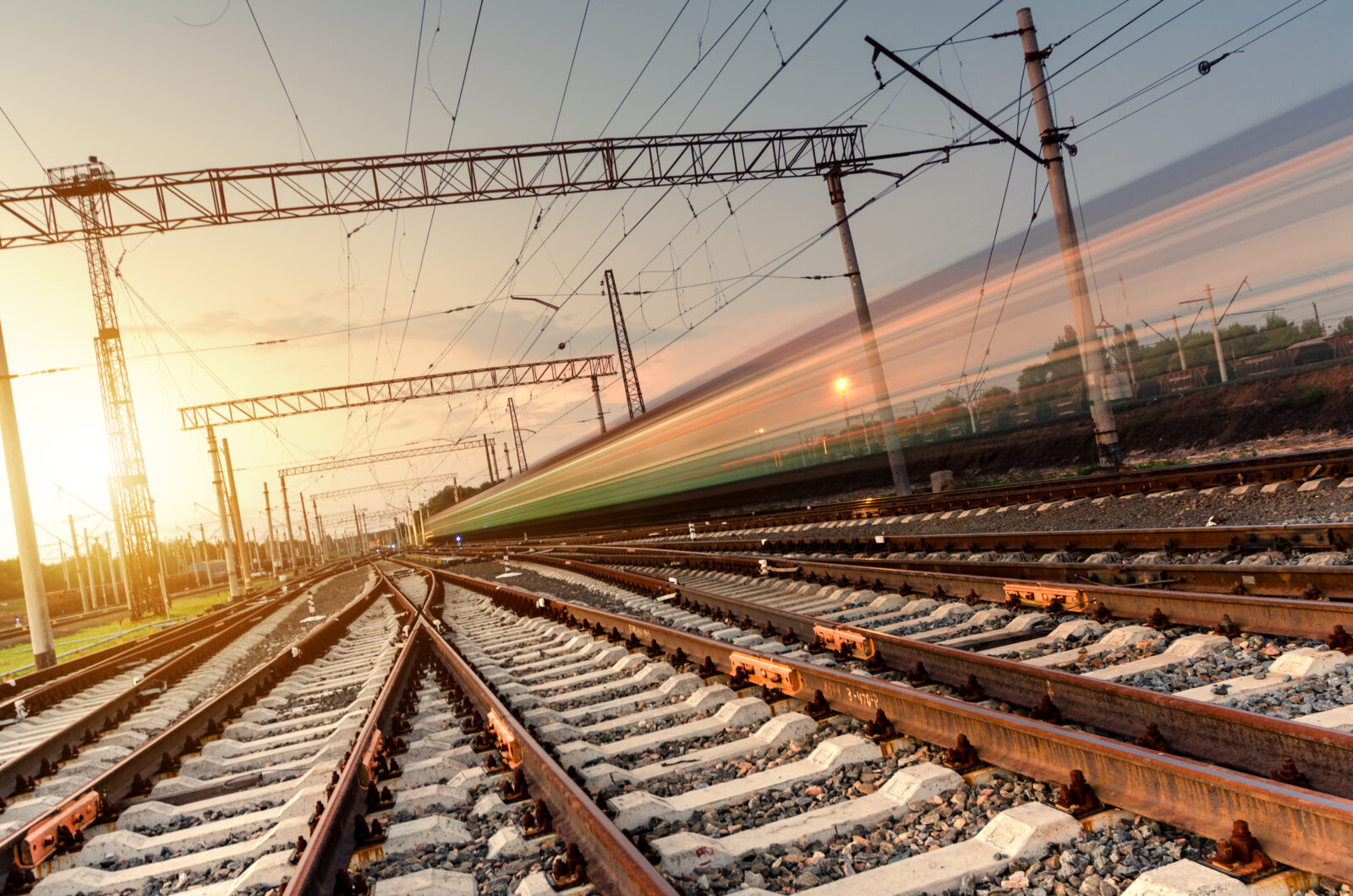 High speed passenger train on tracks with motion blur effect at sunset. Railway station in Ukraine