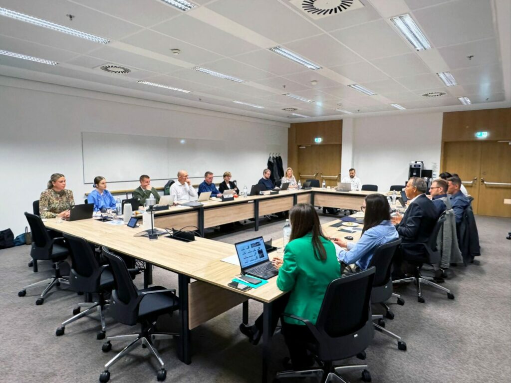 photo showing the meeting room with a table arranged in O-shape with people sitting around it