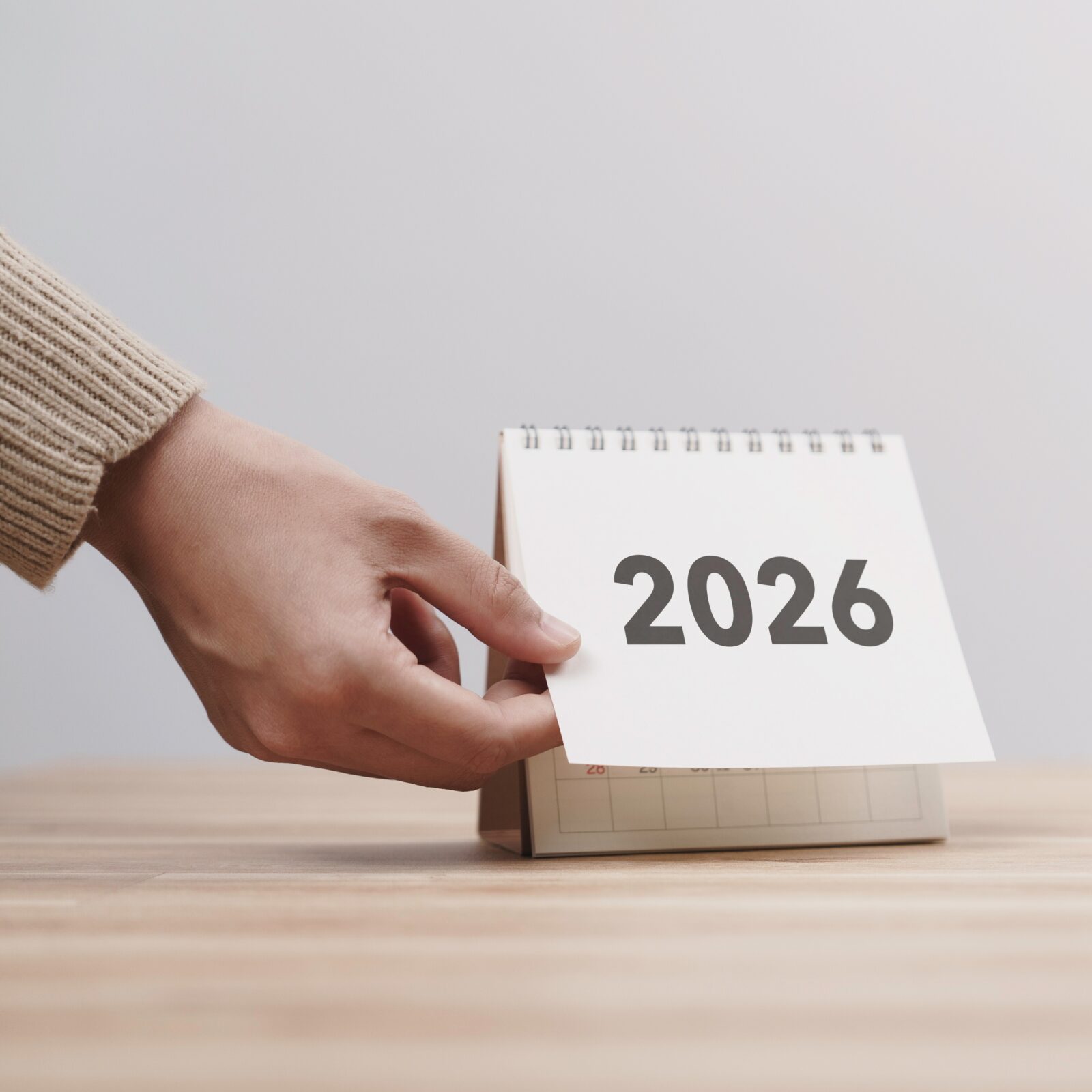 adobestock_1763615058_square Business woman hand change 2026 Year Calendar on table in office background. countdown to Happy New Year, Year End and New Start, Resolution and Goals Plan Action Concept. Schedule in 2026