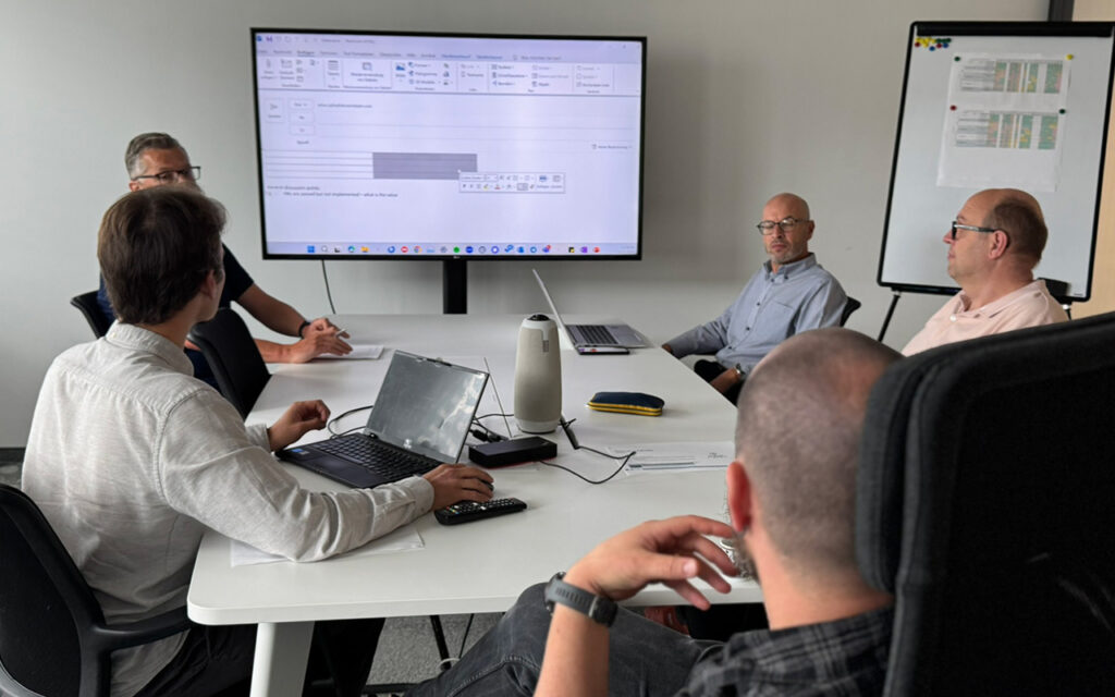 group of 5 workshop participants seated around a table discussing